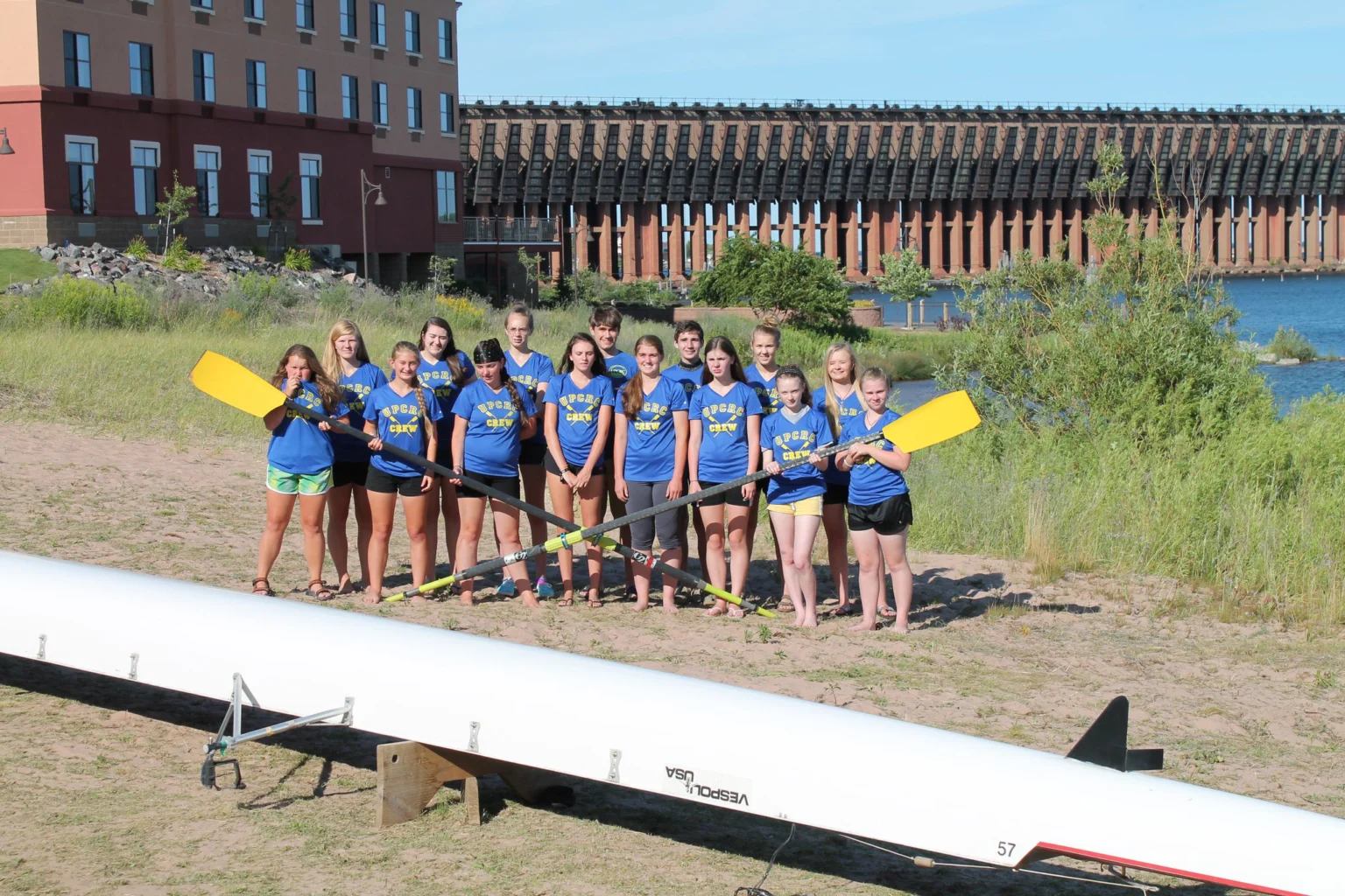 youth rowers with crossed oars standing in front of the ore dock